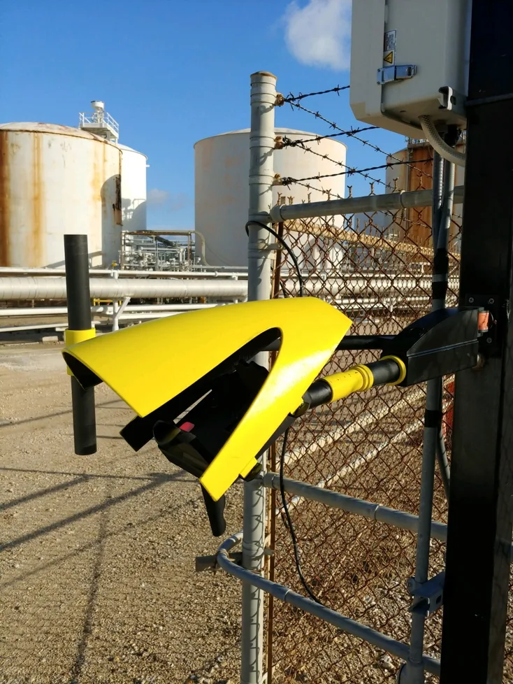 A secured metal vehicle gate with intercom and access controls at a facility entrance