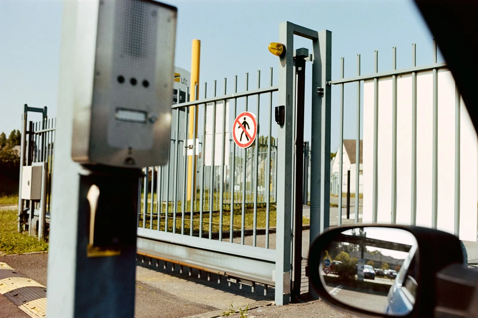 A secured metal vehicle gate with intercom and access controls at a facility entrance